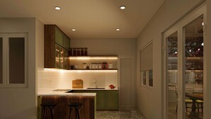 Una cocina moderna con armarios verdes, encimera de mármol y dos taburetes.