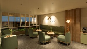 Un área de estar moderna con sillones tapizados en verde, un banco también verde y una cafetera.