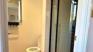 A bathroom with a toilet, a shower enclosure, and a sink. - Newly-built Studio Near Laindon Station (Basildon)