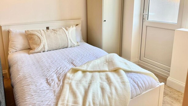 A bedroom with a bed, a wardrobe, and three framed artworks on the wall. - Newly-built Studio Near Laindon Station (Basildon)