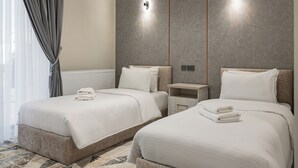 A hotel room with two beds, a small bedside table, a wall-mounted light, and a radiator. - Hotel Shodlik  (Samarkand)
