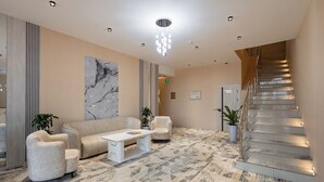 A modern lobby with a marble wall, a staircase, and a patterned carpet. - Hotel Shodlik  (Samarkand)