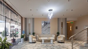 A modern lobby with a sofa, armchairs, a coffee table, and a patterned carpet. - Hotel Shodlik  (Samarkand)