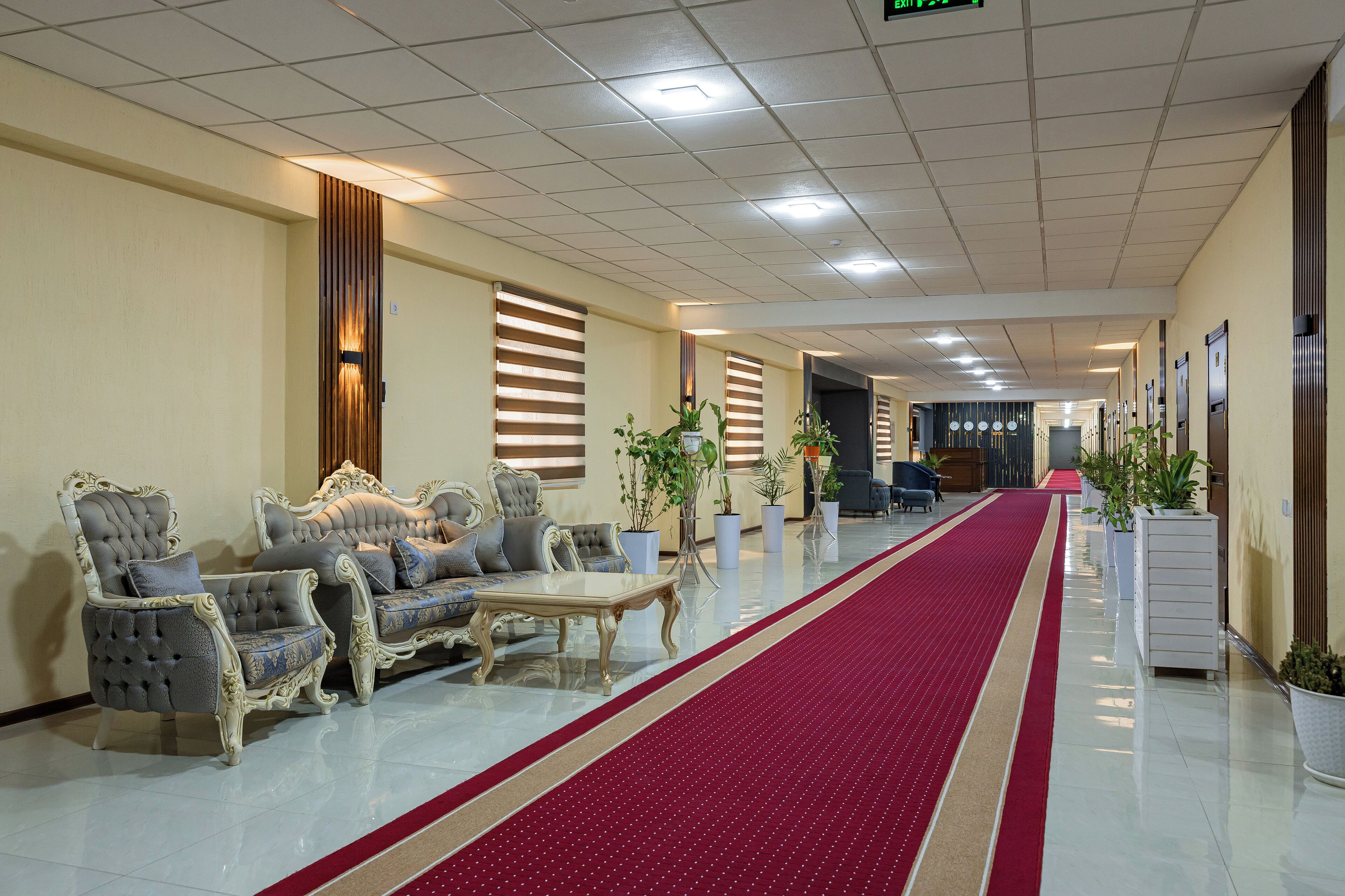 Un hall de hotel con alfombra roja, dos sofás y plantas en macetas.