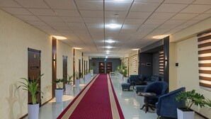 A hotel lobby with a red carpet, potted plants, seating area, and a reception desk. - Hotel Shodlik  (Samarkand)