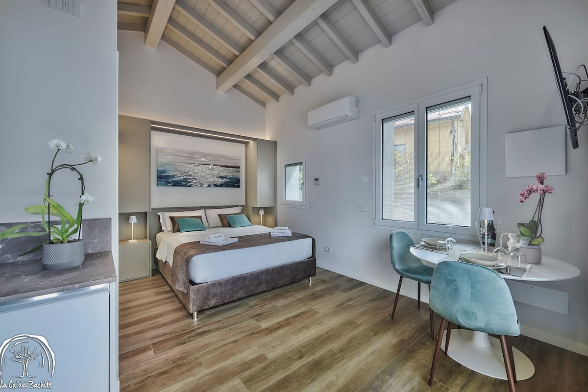 A modern bedroom with a bed, bedside table, and a desk with chairs.