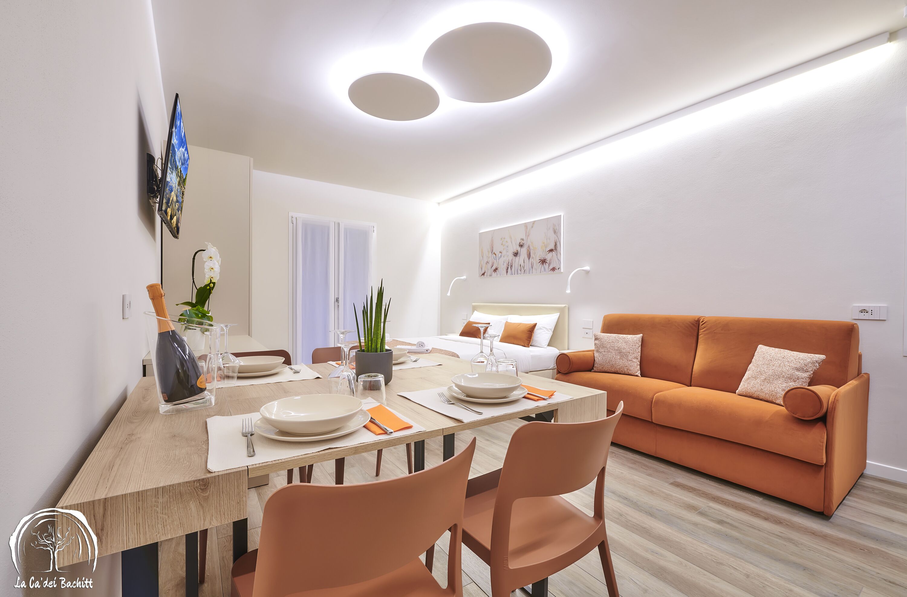Un salon moderne avec un canapé, une table à manger et un téléviseur à écran plat fixé au mur.