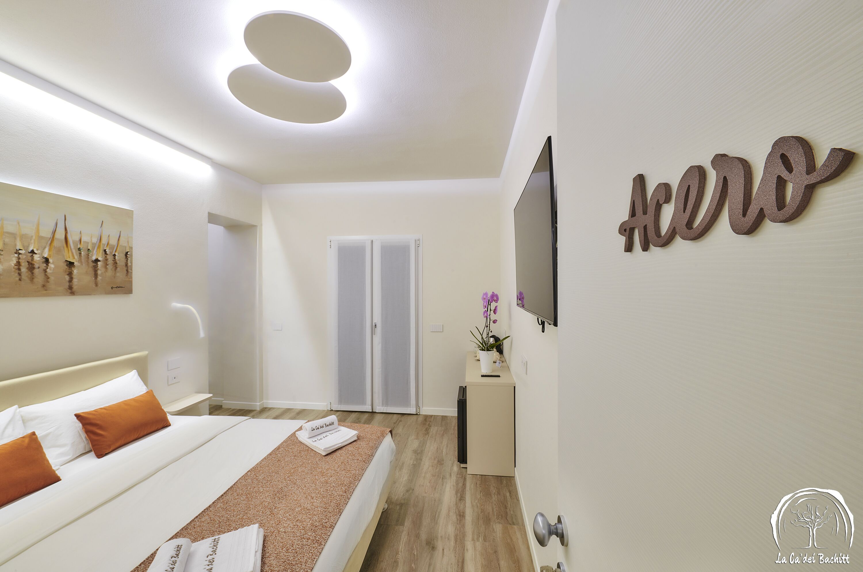 Ein modernes Hotelzimmer mit Bett, Schreibtisch, Fernseher und einem Bild an der Wand.