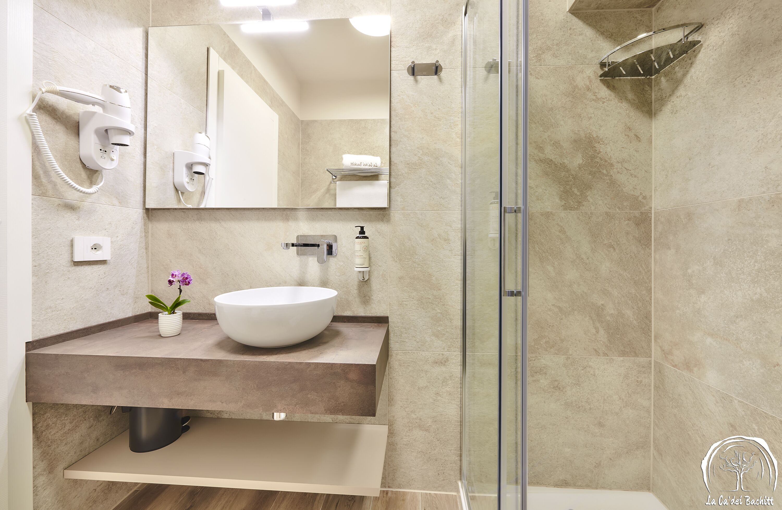 Un baño moderno con un espejo grande, un lavamanos blanco, una ducha y un perchero para toallas.