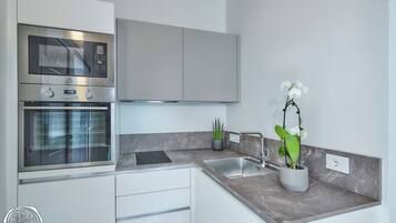 A modern kitchen with stainless steel appliances, a marble countertop, and a potted orchid.