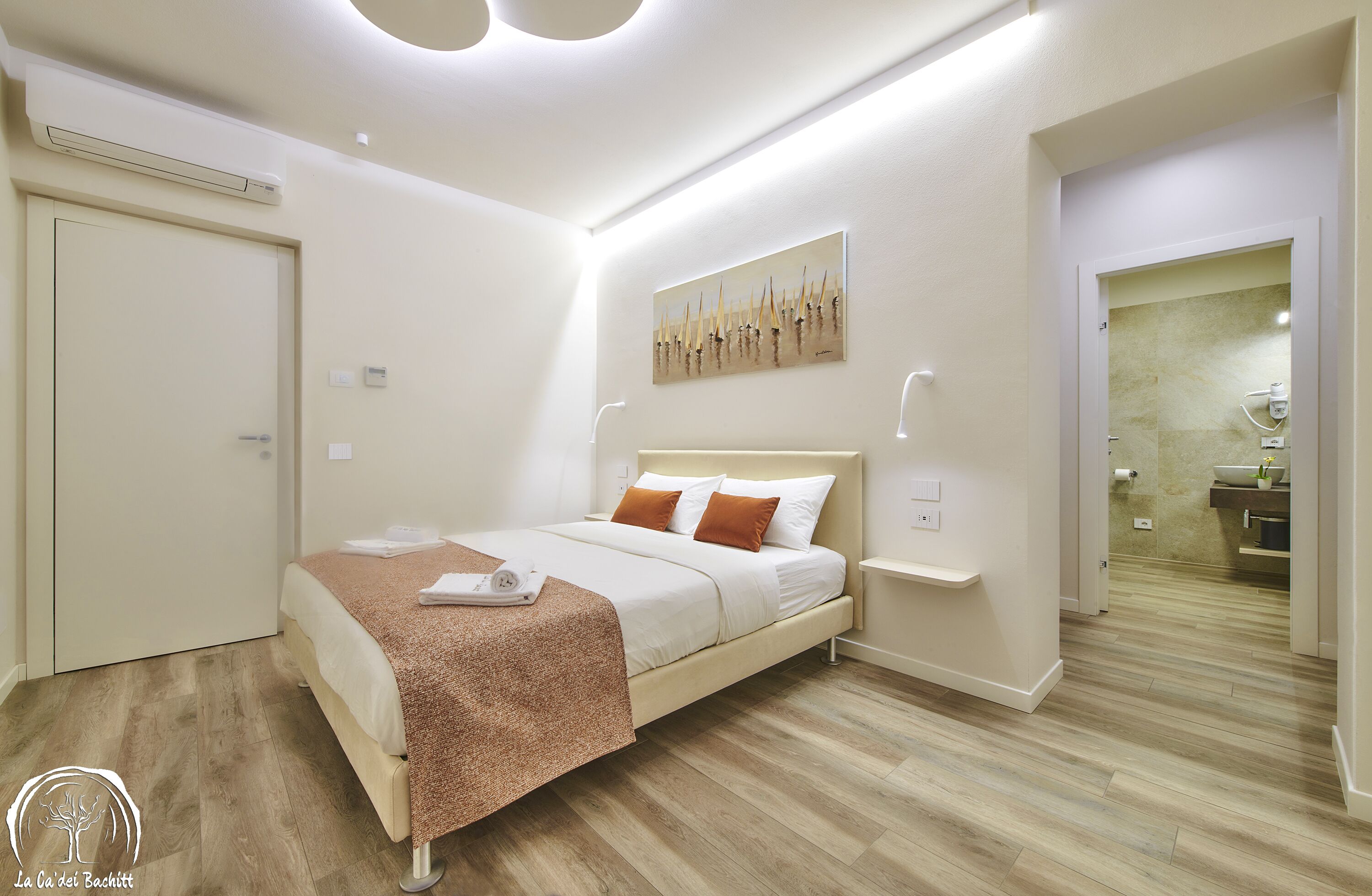 A modern bedroom with a bed, bedside tables, and a bathroom visible through an open door.