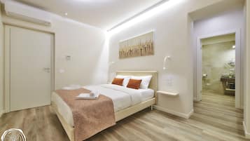 Ein modernes Schlafzimmer mit einem Bett, Nachttischen und einem durchgegangene Tür erkennbaren Badezimmer.