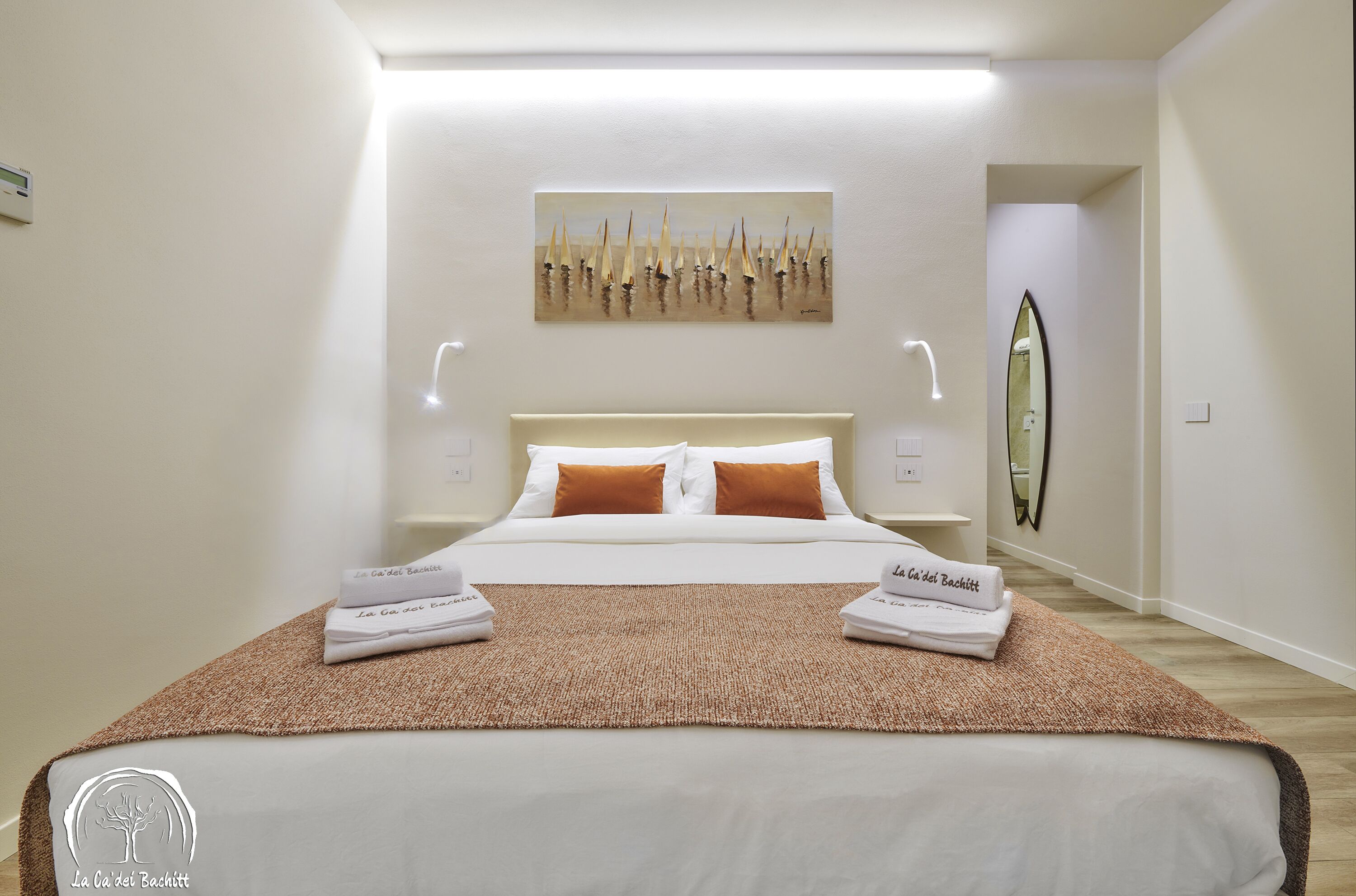 Una habitación de hotel con una cama bien hecha, un cuadro en la pared y un espejo.