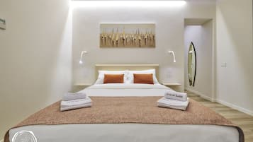 Een hotelkamer met een net opgemaakt bed, een schilderij aan de muur en een spiegel.