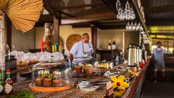 Uma área de bar com balcão de madeira, vitrines de vidro e diversos itens alimentícios.