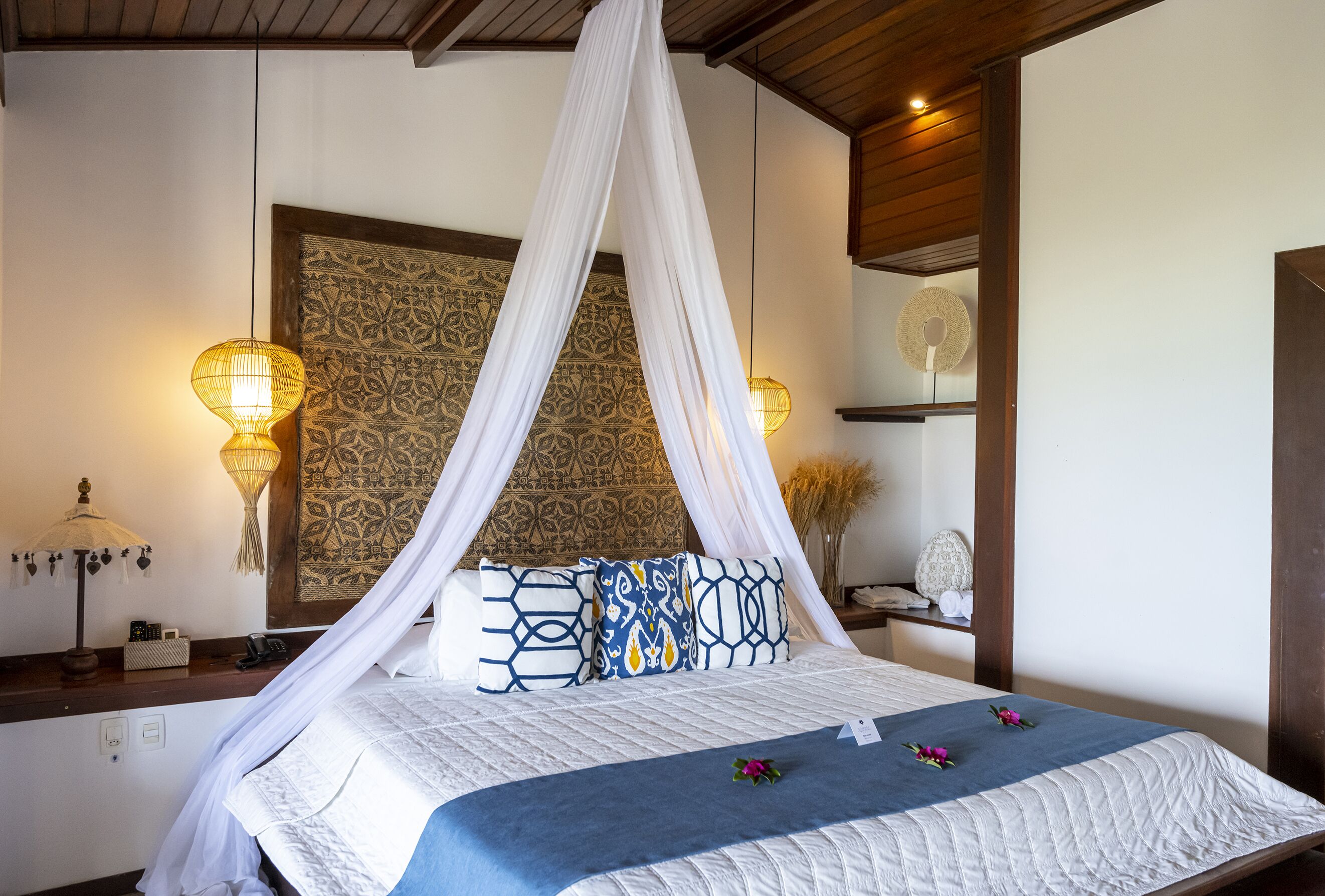 A bed with a canopy, patterned wall, and bedside lamps.