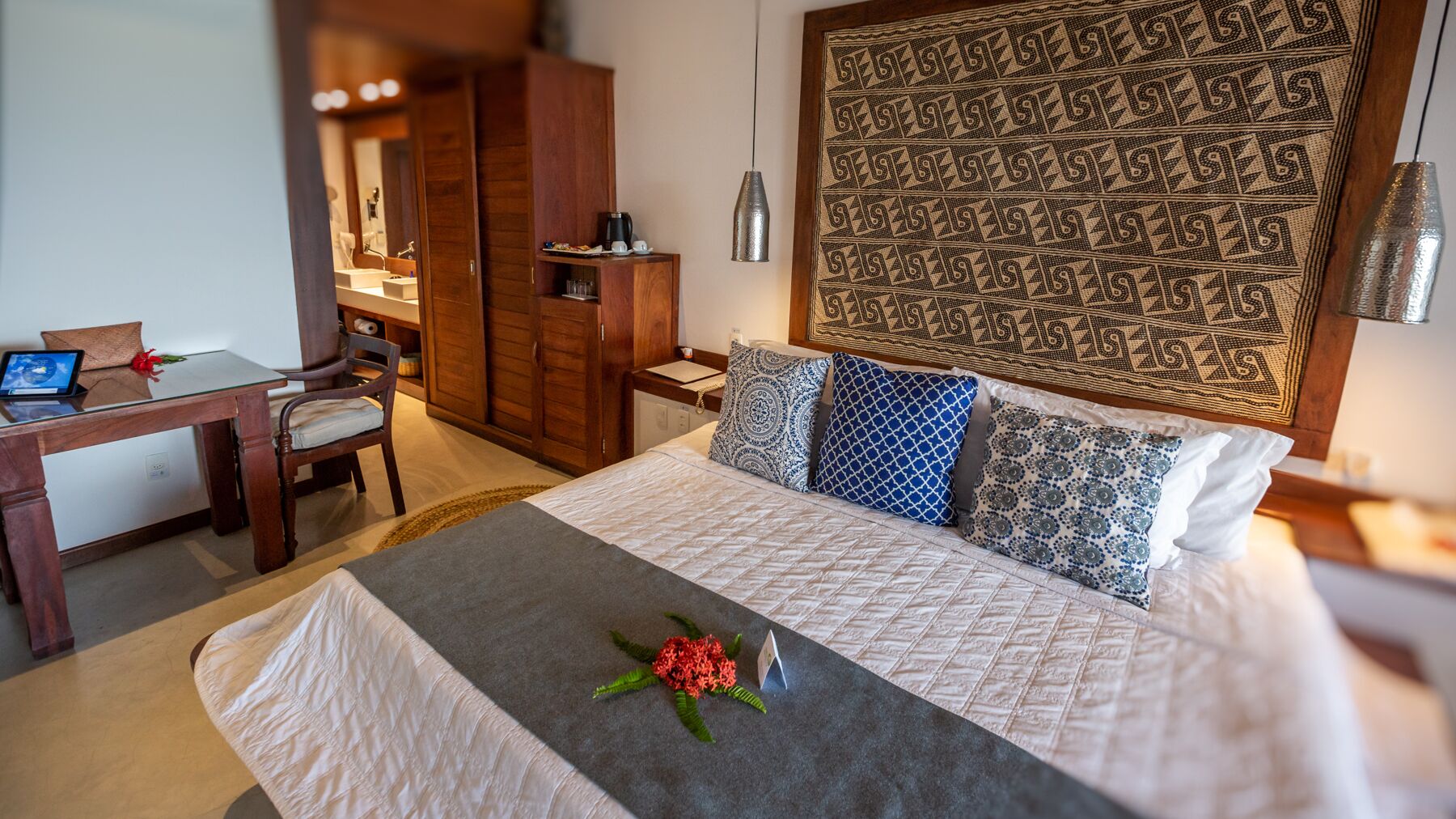 A neatly arranged hotel room with a bed, a desk, and a wardrobe.