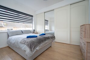 Relax in this serene bedroom with a large bed, a wardrobe, and a dresser.