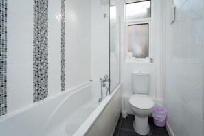 Bathroom features a bathtub and toilet, with a window above.