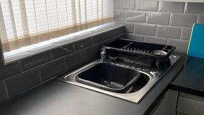 A kitchen with a black countertop, stainless steel sink, and a dishwasher.