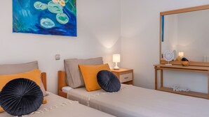 Ein Hotelzimmer mit zwei Betten, einem Nachttisch mit Lampe, einem Spiegel und einem Bild an der Wand.