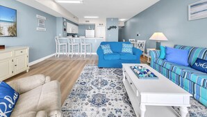 A living room with a blue sofa, a white coffee table, and a patterned rug. - 🌊Beachfront Complex-2BR Shores of Panama 1202🌊 (Panama City Beach)