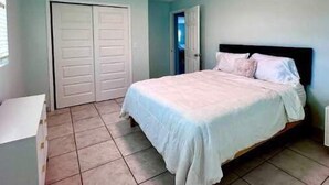 A bedroom with a bed, a white dresser, and a closet.