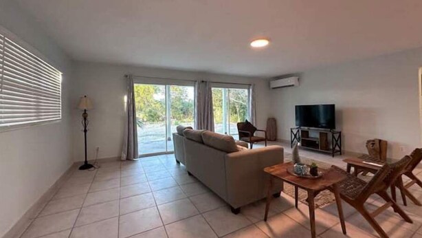 A living room with a sofa, a TV, and a dining area with chairs.