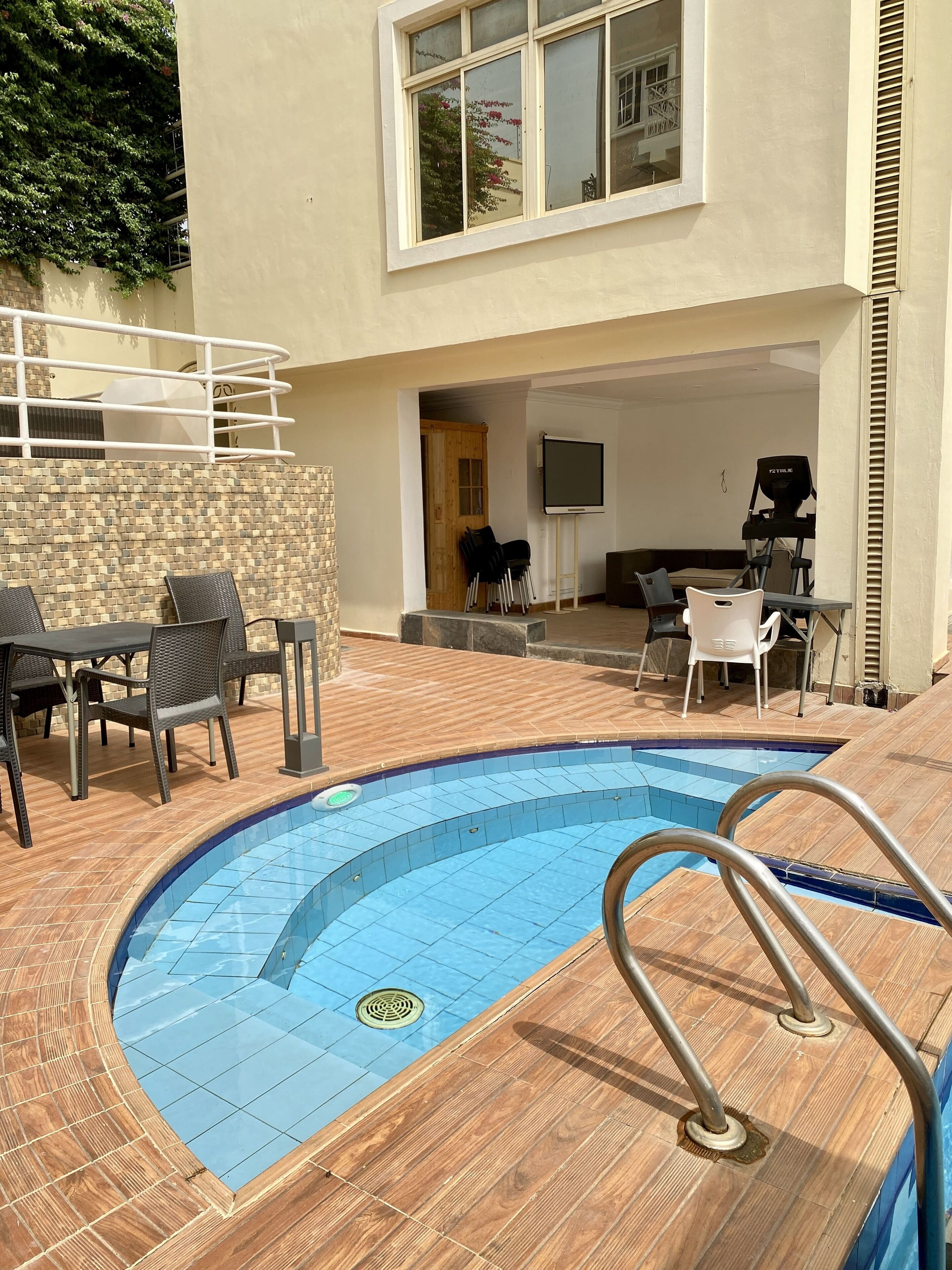 A swimming pool with a wooden deck, a TV, and outdoor seating.
