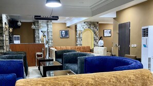 A hotel lobby with seating areas, a reception desk, and a large mirror. - Glovis Luxury Apartments (Abuja)