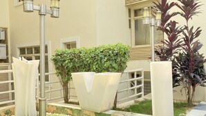 A well-maintained outdoor area with a paved walkway, a grassy lawn, and a variety of potted plants. - Glovis Luxury Apartments (Abuja)