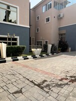 A building with a paved courtyard, multiple windows, and outdoor lighting fixtures.
