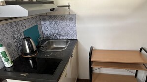 A compact kitchen with a sink, a kettle, and a small table.