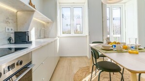 Eine moderne Küche mit weißen Schränken, einem Einbauofen und einem Essbereich mit gedecktem Frühstückstisch.