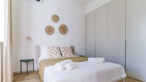 Ein ordentlich eingerichtetes Schlafzimmer mit einem Bett, Kissen, einem Nachttisch und einem Kleiderschrank.