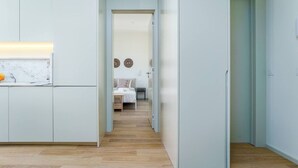 A narrow hallway with a kitchen on the left, a bedroom with a bed and nightstand in the center, and a door on the right. - Modern & Cozy Faro Mercado Apt 21 by Lisbeyond (Faro)