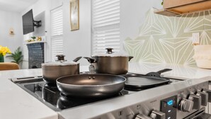 Une cuisine moderne équipée d’une cuisinière à gaz, de deux casseroles et d’une poêle sur le plan de travail.
