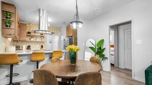 Une cuisine moderne avec un îlot central, des chaises en bois et un luminaire suspendu.