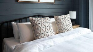 Une chambre à coucher comprenant un lit, deux lampes fixées au mur et deux œuvres d’art encadrées.