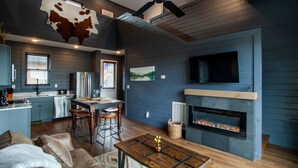 Une cuisine moderne dotée d’une cuisinière intégrée, de tabourets de bar et d’un coin repas avec une table et des chaises en bois.