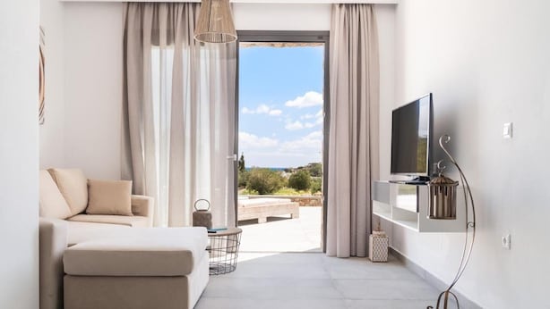 Una sala de estar moderna con un sofá, un televisor montado en la pared y vistas al exterior.