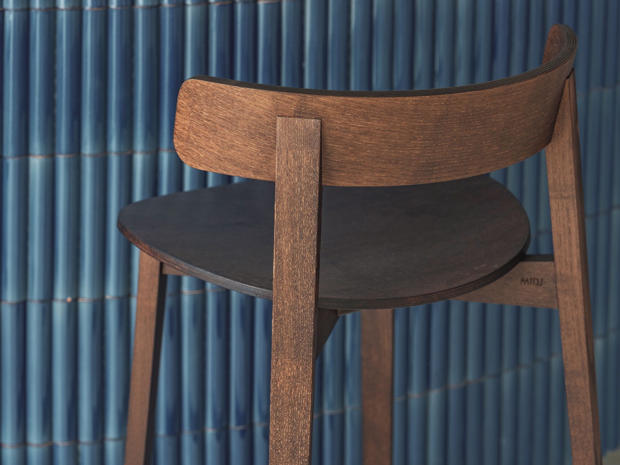 Une chaise en bois, avec un siège et un dossier de couleur foncée, placée devant un fond en métal ondulé.