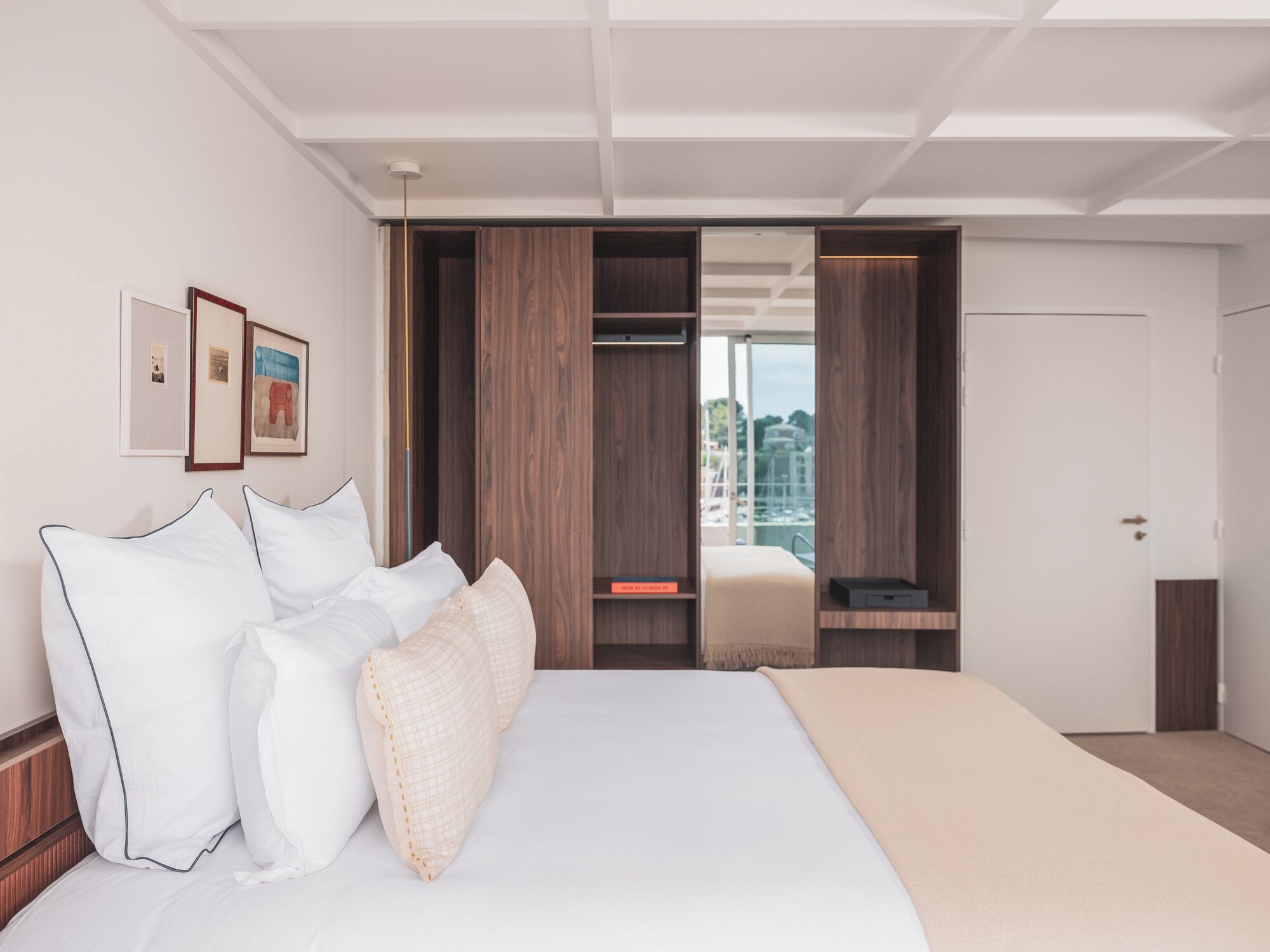 Habitación de hotel moderna con una cama grande, armario de madera y vistas a la ciudad.