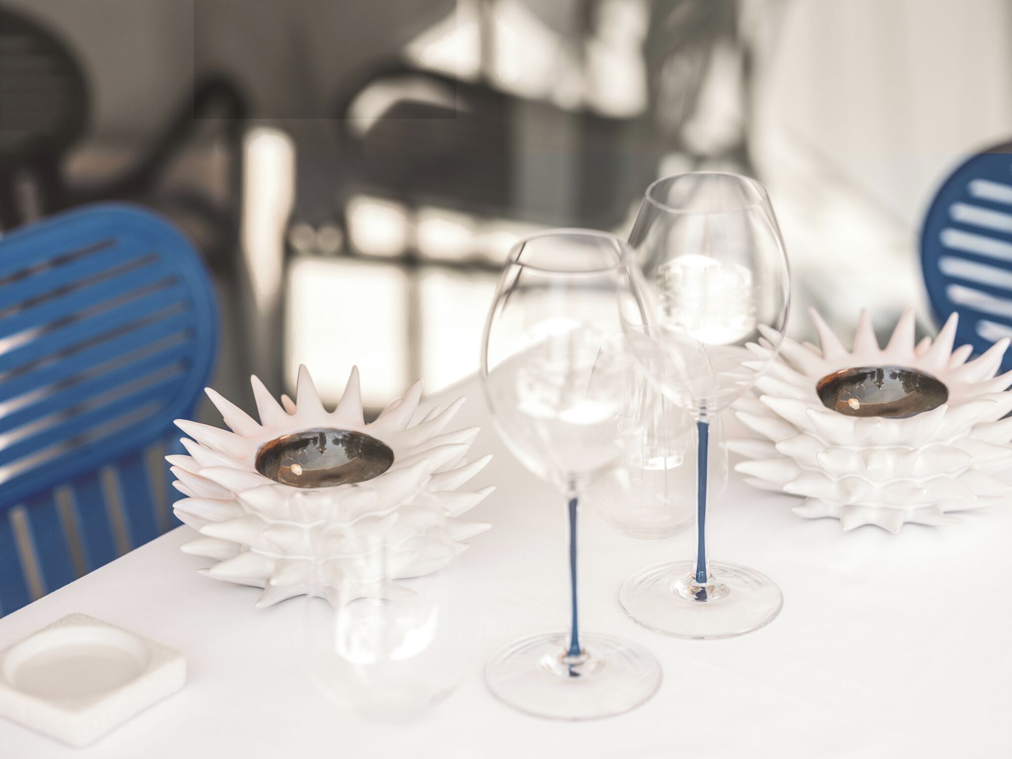 A table with three wine glasses on white floral coasters.