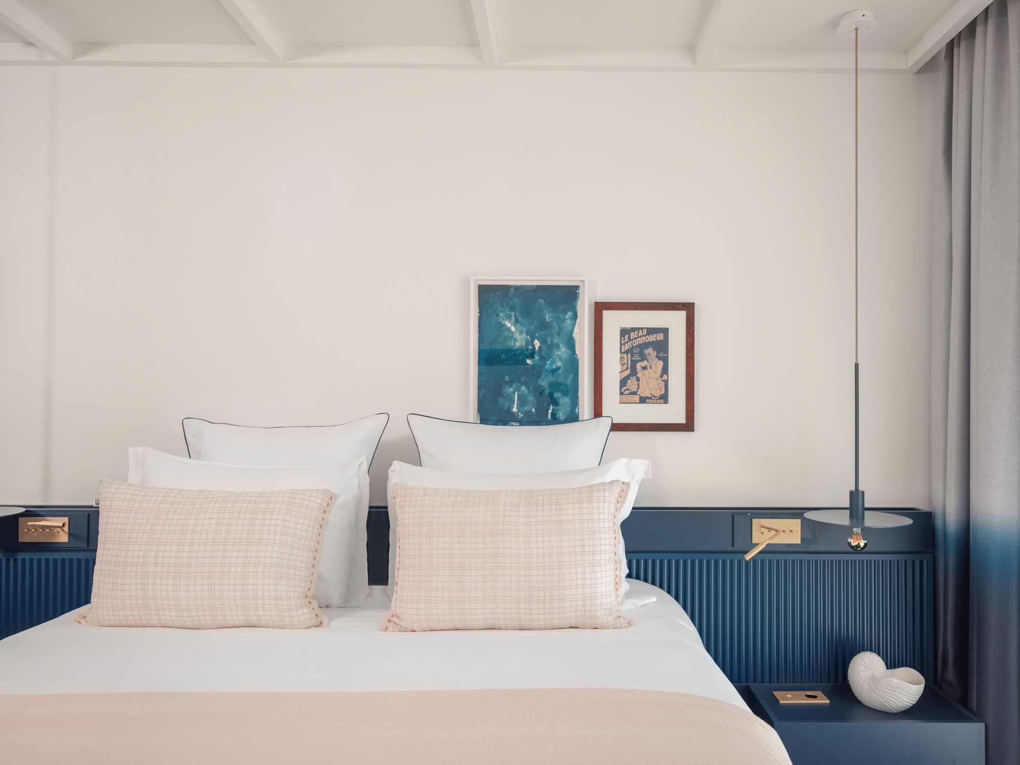 A modern hotel room with a large bed, two bedside tables, a wall-mounted artwork, and a floor lamp.