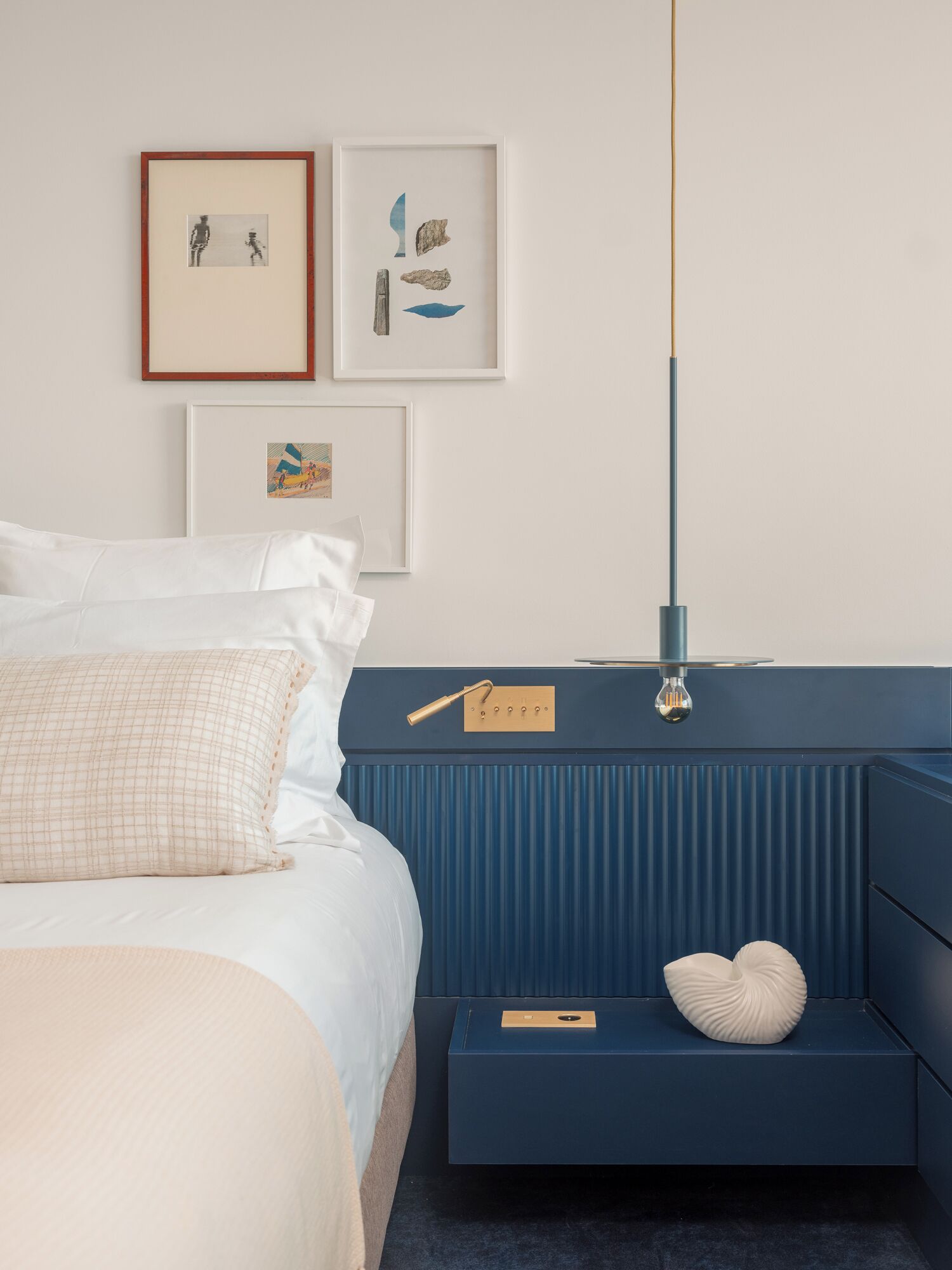 A bedroom with a bed, bedside tables, and wall-mounted artwork.