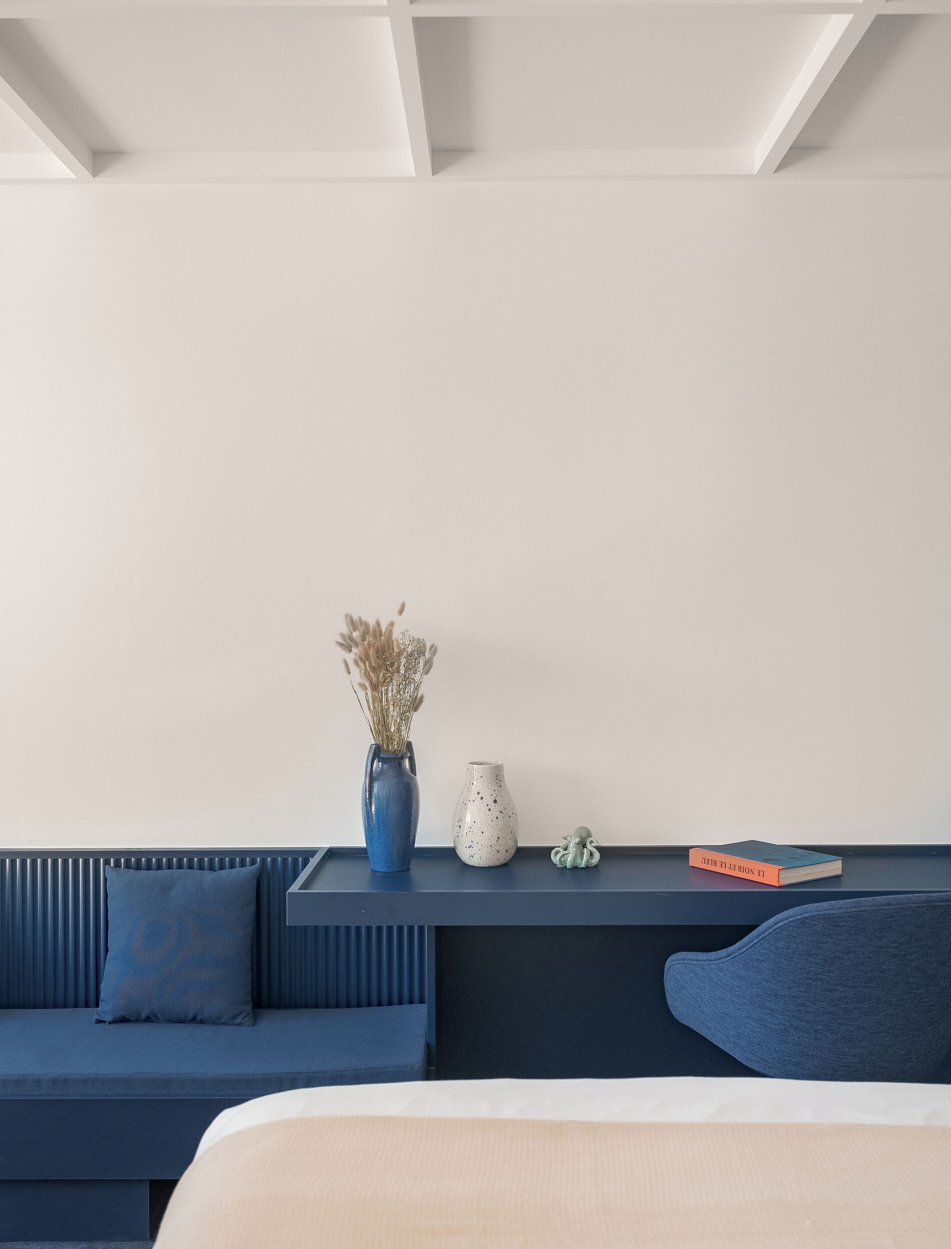 A modern room with a blue sofa, a small table with decorative items, and a white wall.