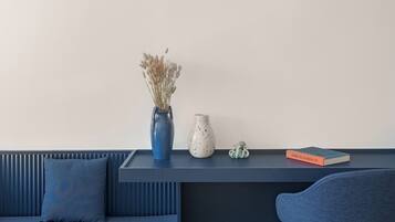 A modern room with a blue sofa, a small table with decorative items, and a white wall.
