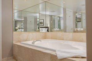 Une salle de bain moderne avec une grande baignoire, un miroir et un tableau encadré au mur.