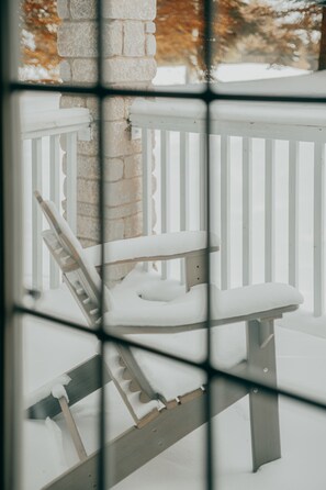 Un espace extérieur enneigé, avec un banc en bois et un pilier en pierre.